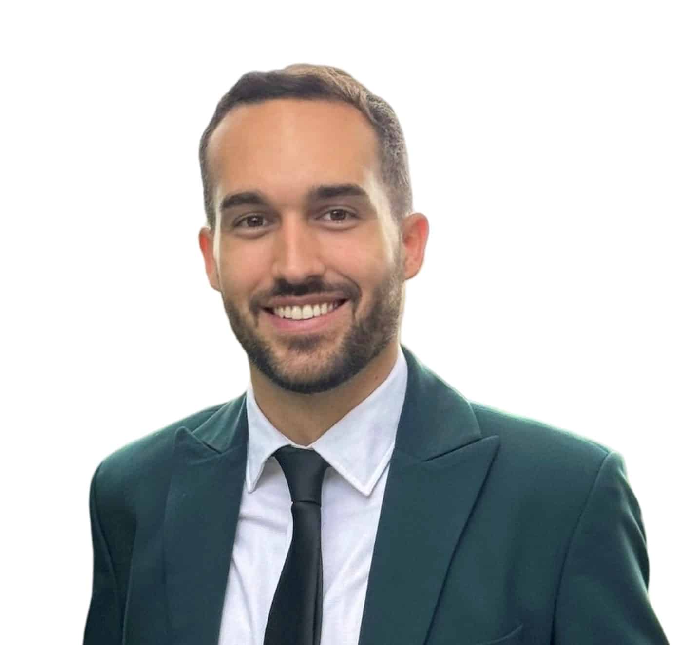 A smiling man with short dark hair and a beard, wearing a dark green suit jacket, white dress shirt, and black tie, posed in front of a plain white background, celebrating the ACI World Technology Innovation Awards.