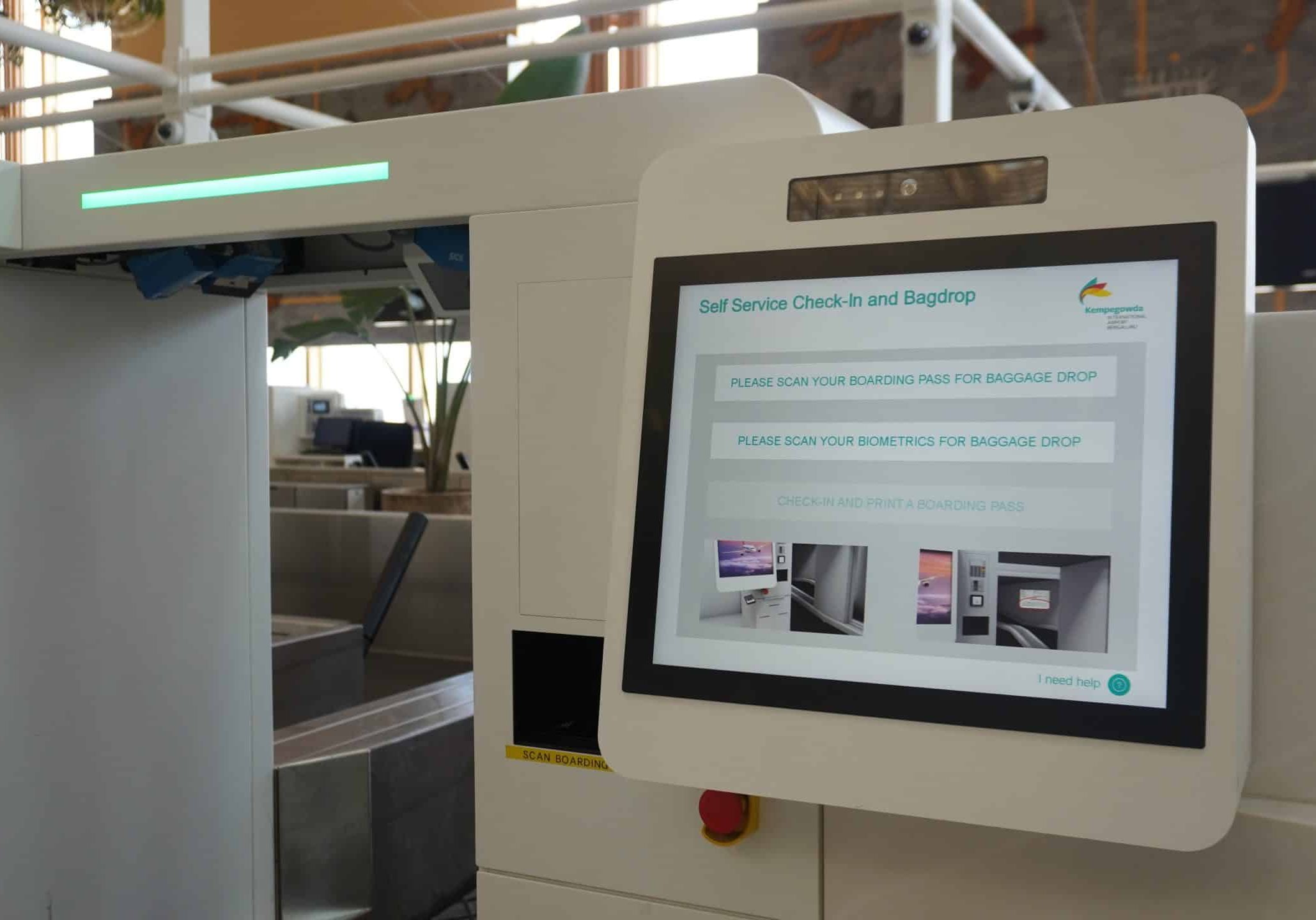 A close-up of an airport self-service kiosk screen displaying instructions for check-in and bag drop, with a baggage conveyor belt visible beside it—a scene showcasing advancements recognized by the ACI World Technology Innovation Awards.